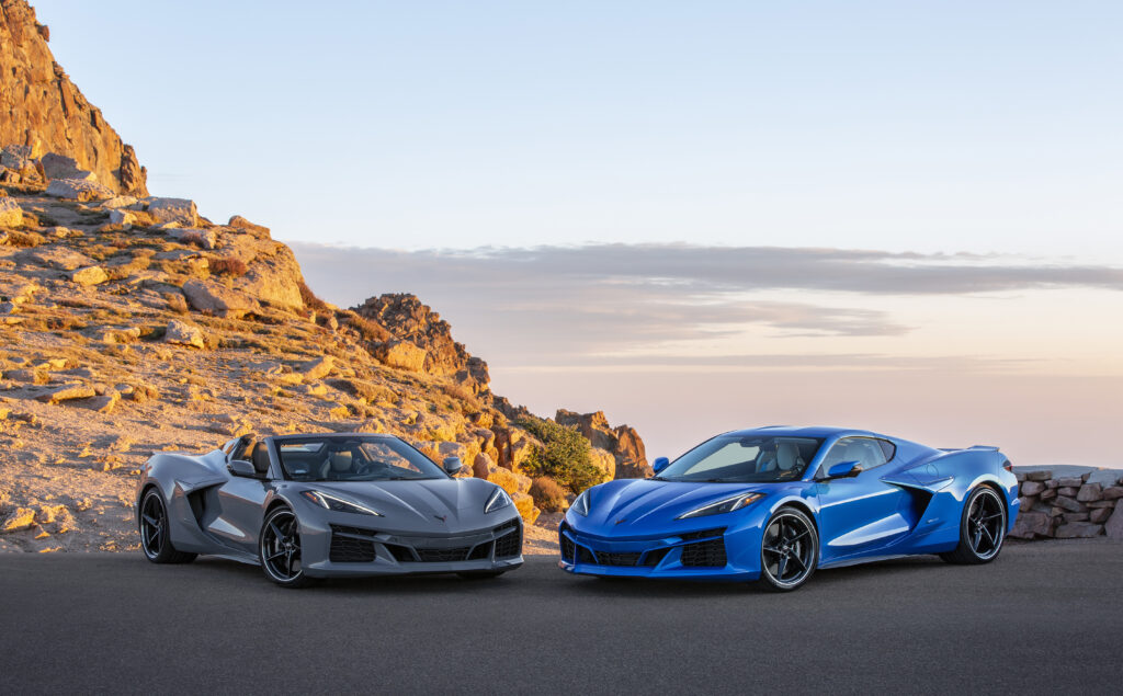 Front 3/4 view of a 2024 Corvette E-Ray 3LZ convertible in Sea Wolf Gray Tricoat and a 2024 Corvette E-Ray 3LZ coupe in Riptide Blue Metallic parked on a mountain overlook. Pre-production model shown. Actual production model may vary. Model year 2024 Corvette E-Ray available 2023.