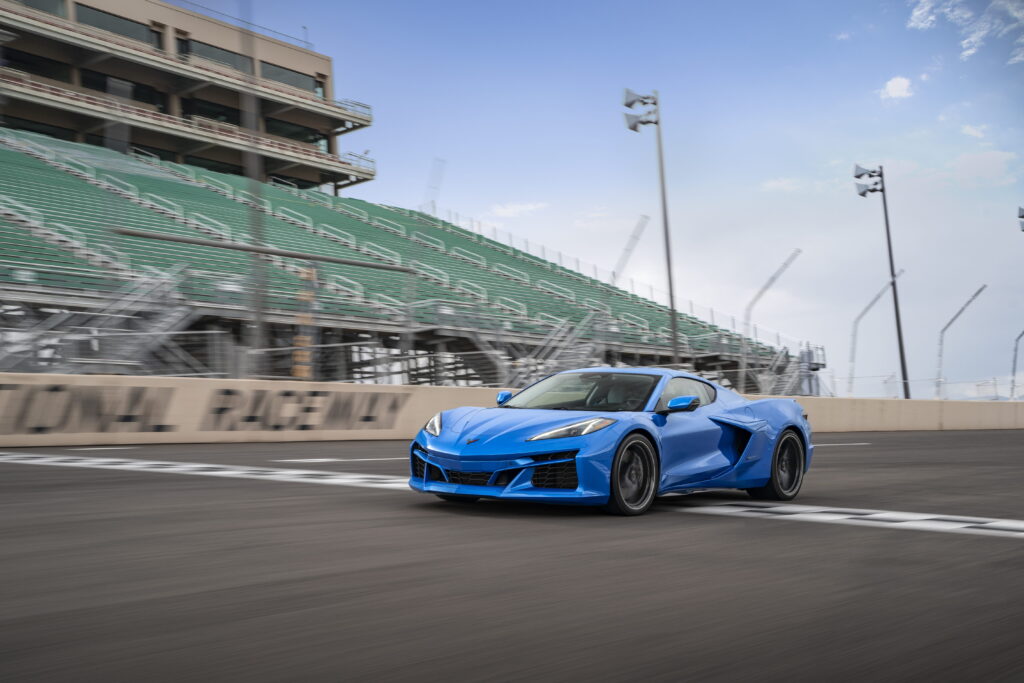 Front 3/4 view of a 2024 Corvette E-Ray 3LZ coupe in Riptide Blue Metallic crossing the finish line on a track. Pre-production model shown. Actual production model may vary. Model year 2024 Corvette E-Ray available 2023.
