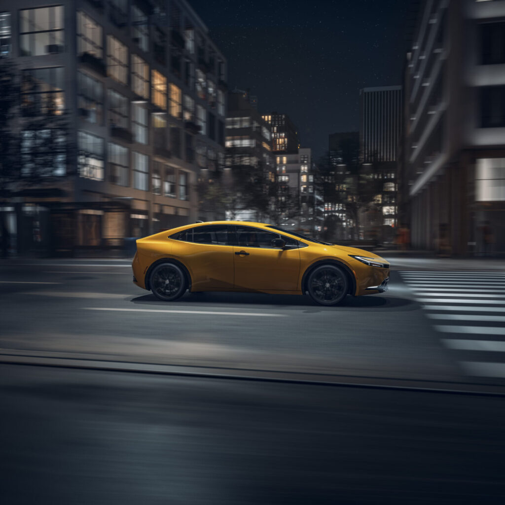 2026 Toyota Prius nightshade in yellow driving through the city at night