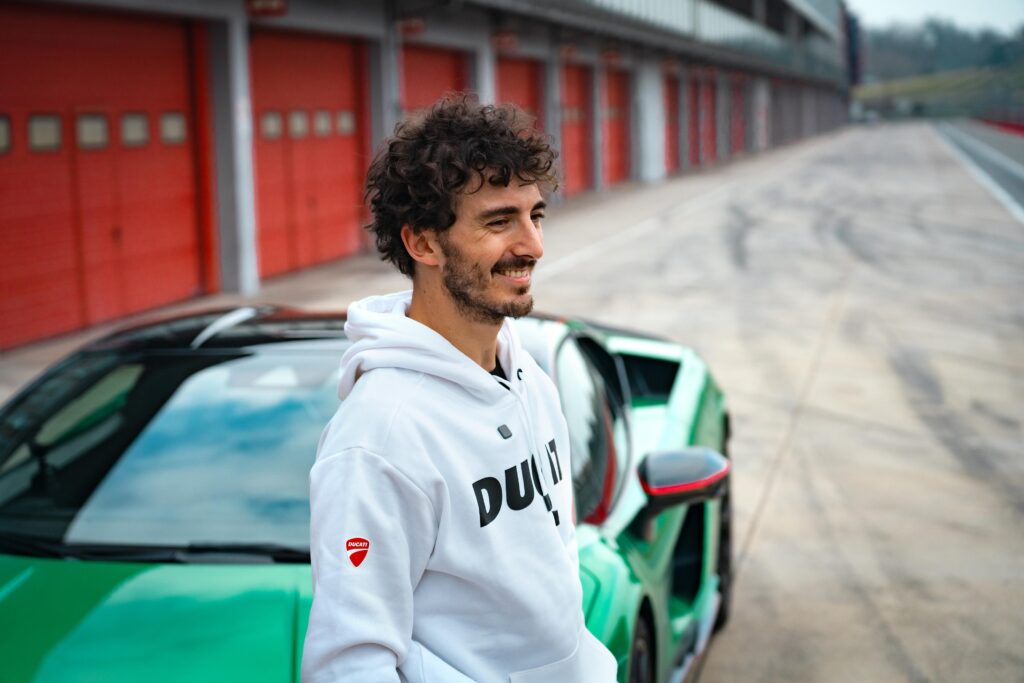 Francesco ‘Pecco’ Bagnaia leans up against the Lamborghini on the track