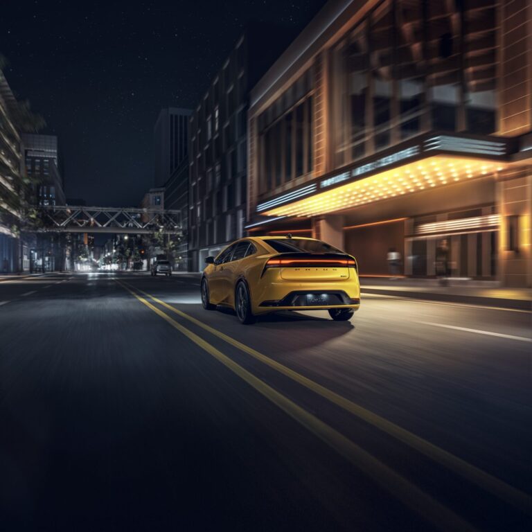 Yellow 2026 Prius driving down the street at night