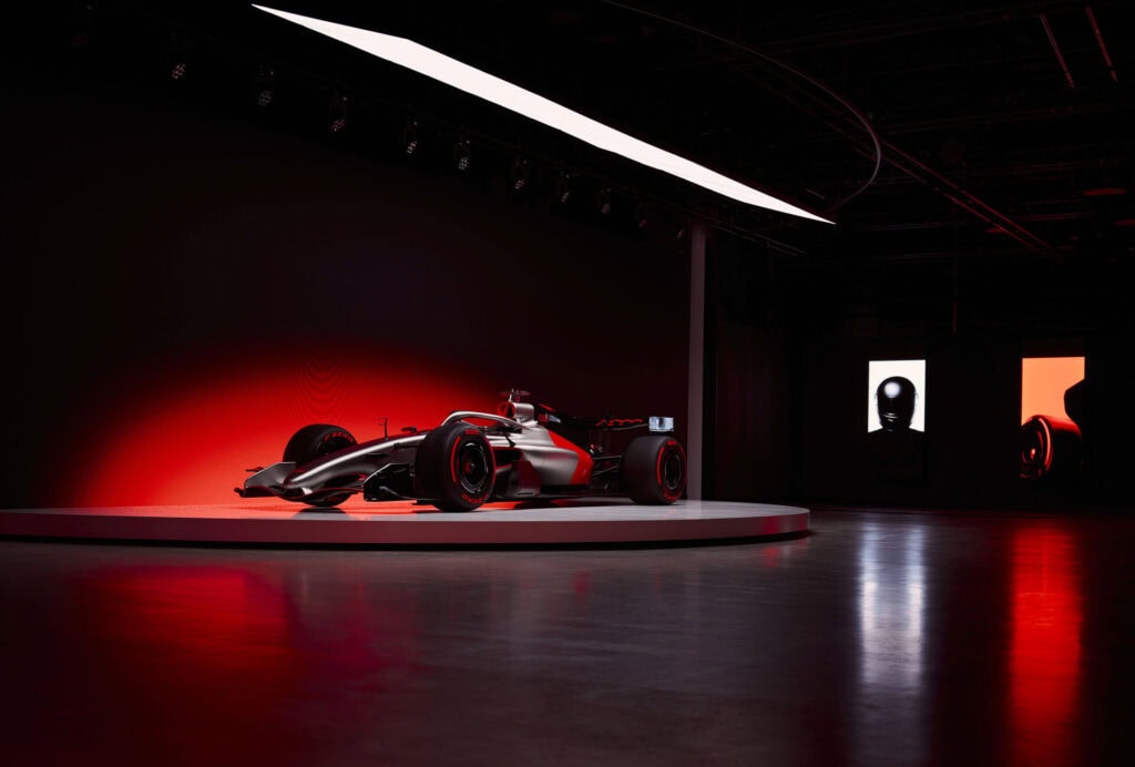 Audi F1 R26 on stage with a red glow nehind it.