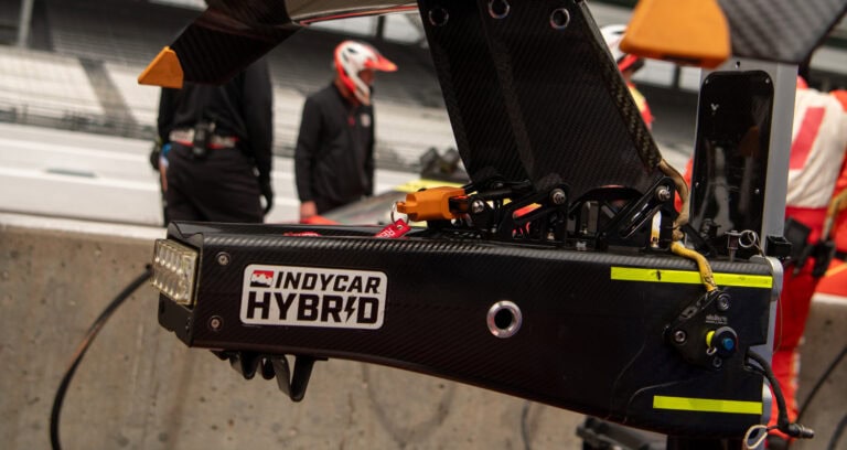 Rear-end of an Indy Car with a sticker that says "INDYCAR Hybrid"