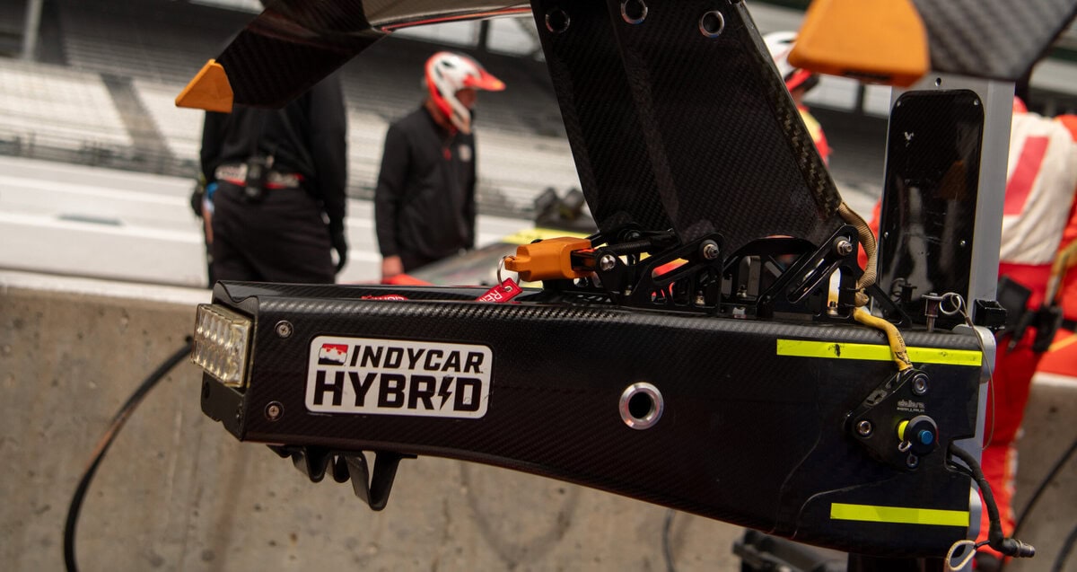 Rear-end of an Indy Car with a sticker that says "INDYCAR Hybrid"