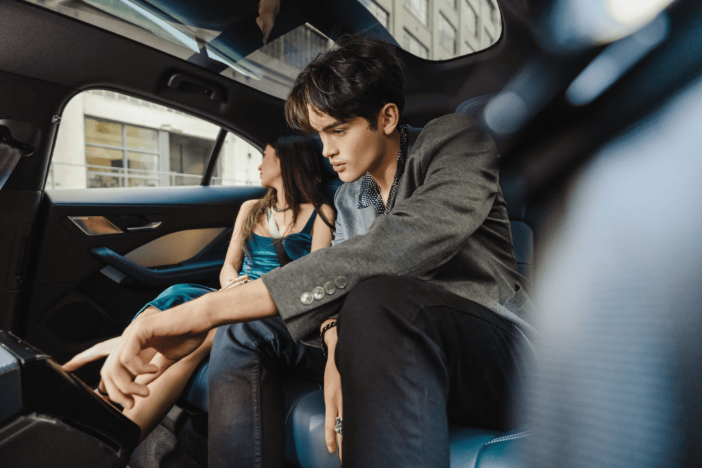 Two people in the back seat of a Waymo vehicle interacting with the screen